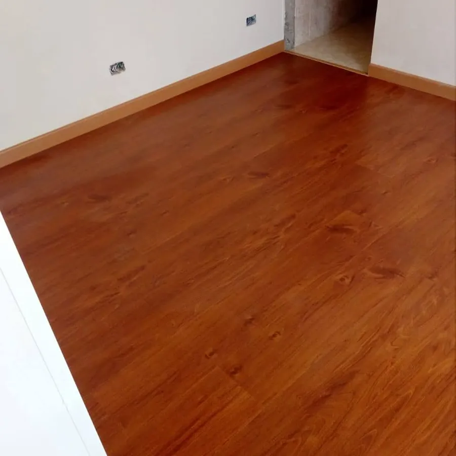 Habitación con piso laminado tono cerezo ya instalado y con guardaescobas